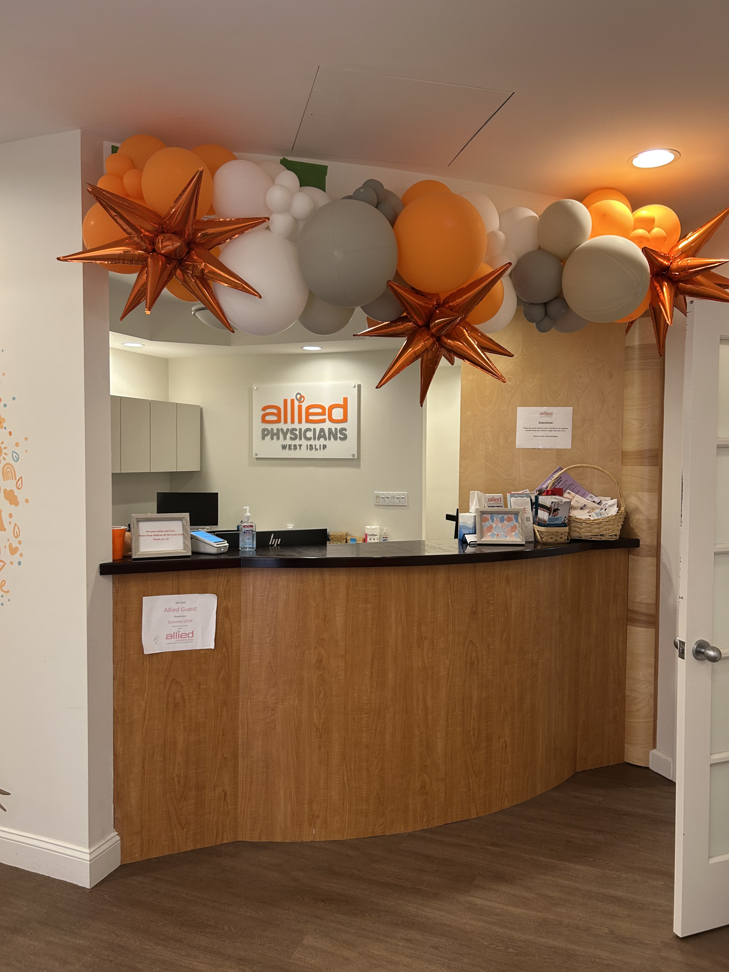 Reception desk at Allied Physicians West Islip decorated with a balloon arch featuring metallic star-shaped balloons.