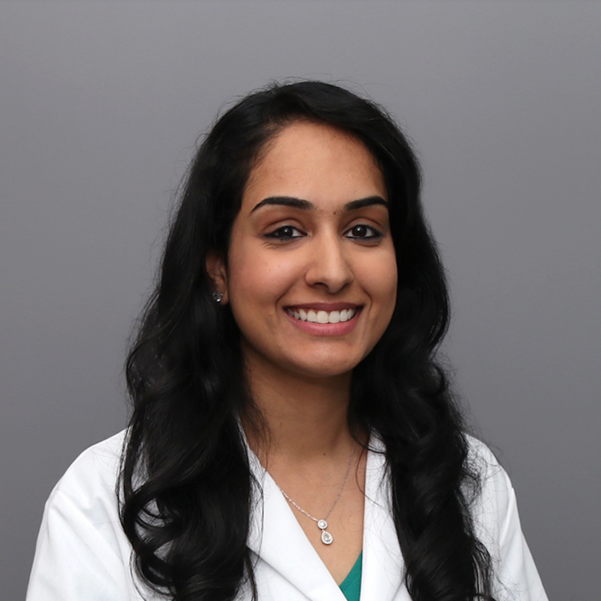 A smiling woman in a white medical coat.