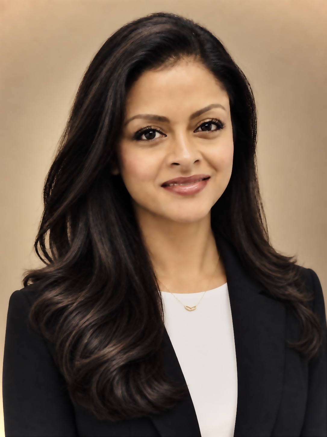 A professional headshot of a smiling woman with long dark hair wearing a black blazer over a white shirt.